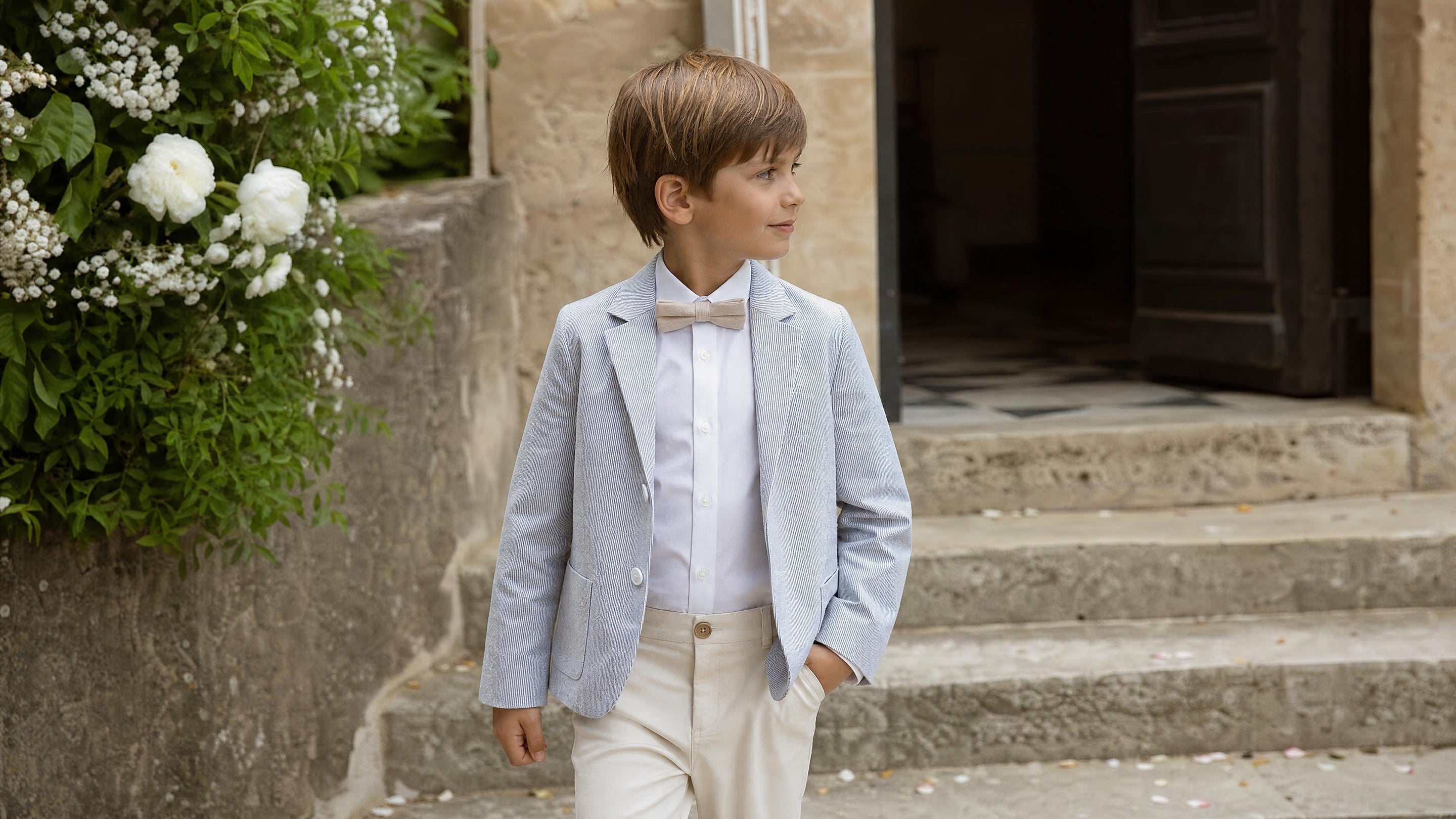 Garçon en tenue de cérémonie avec accessoires adaptés pour un mariage.