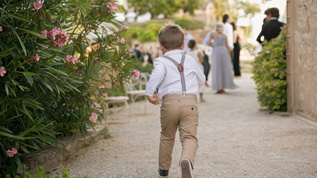Enfant portant des bretelles pour une cérémonie, tenue élégante et naturelle. Bild